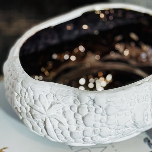 A white ceramic decorative bowl with a floral pattern and a reflective surface.